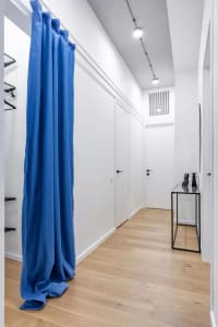 Modern closet with blue curtain, white walls, and white flooring.