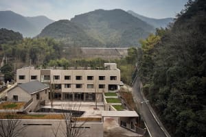 A modern residential building made of concrete with a minimalist design and surrounded by greenery.