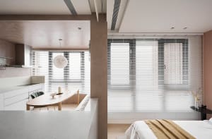 A modern residential interior with a kitchen and dining area featuring concrete walls, wooden furniture, and glass windows.