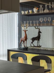 A modern bar with black metal deer statues on the counter, illuminated by ambient lighting, and adorned with glassware and de