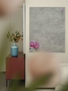 A modern living room with a grey wall, a red cabinet, a blue vase with flowers, and a painting of a pink flower on the wall.