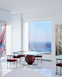 Modern living room with glass table, metal chairs, and red fabric seating.