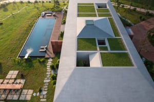 Aerial view of a modern house featuring large concrete structures and glass elements.