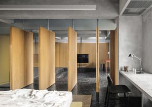 A modern minimalist living room with concrete and wooden elements.