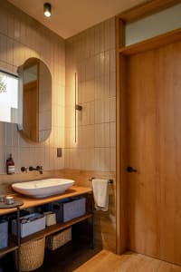 Modern bathroom with minimalist design, featuring neutral-colored tiles and wooden accents.