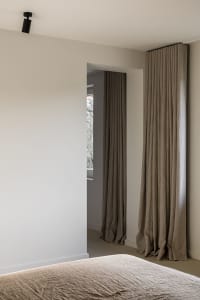 A minimalist bedroom with textured linen curtains, showcasing a serene and stylish bedroom design.