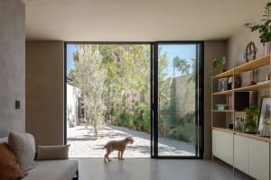 A minimalist residential interior with large glass windows and concrete floors.