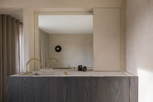 A minimalist residential interior featuring stone countertops, wooden cabinets, and metal faucets.