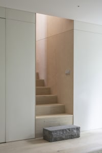 Modern minimalist staircase interior with wood stairs and white walls.