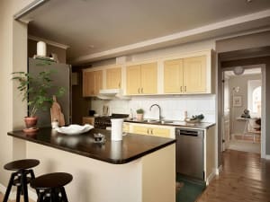 A cozy kitchen featuring yellow cabinets, a wooden counter, and a modern stove.