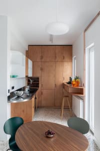 A minimalist kitchen featuring wooden cabinets, metallic countertops, and glass elements.