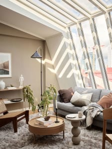 A minimalist living room with a round wooden table, floral arrangement, and white decor elements.