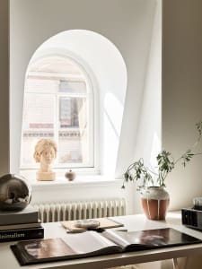 A minimalist desk space featuring a plant, ceramic vase, and books.