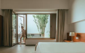 A minimalist bedroom featuring a glass door and a view of nature.