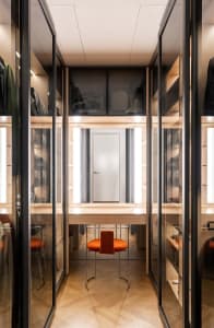 Modern minimalist wardrobe with glass panels and a wooden floor.