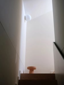 Minimalist interior design featuring a wooden staircase with modern lighting.