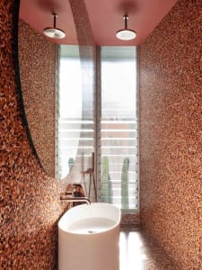 A modern bathroom featuring rustic terrazzo flooring and walls, with a white sink and sleek, minimal design.