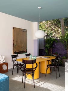 Modern, stylish dining room with a yellow metal dining table and black chairs.