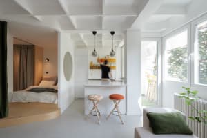 A modern open-concept apartment with a white color scheme and wooden accents.