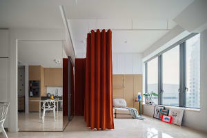 A modern apartment interior with red curtains, open-plan layout, and minimalist design.
