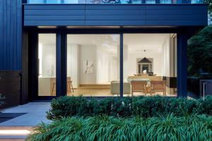 Modern residential interior with large glass walls and wooden furniture.