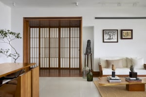 A minimalist living room with white walls and wooden furniture, featuring a white sofa, coffee table, and decorative elements