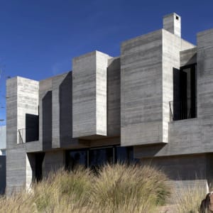 Modern residential house with concrete exterior walls and large windows.