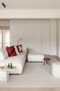 Modern living room with a white fabric sofa, red accent pillows, and a marble coffee table.