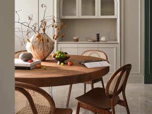 A modern dining space featuring wood furniture, a fruit bowl, and decorative vases.
