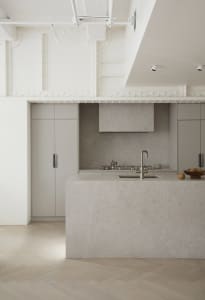 Modern, minimalist kitchen featuring a concrete countertop and sleek, gray cabinetry.