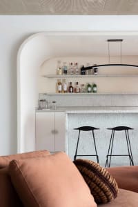 A modern living room featuring a concrete accent wall and bar area.
