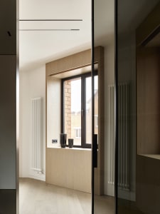A modern interior design featuring a wooden window with a view of a neighboring building.