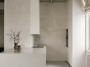 A minimalist kitchen featuring modern design elements with a concrete countertop and white cabinets.