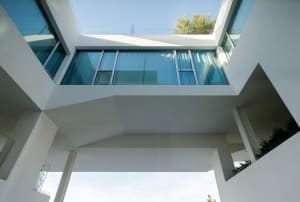 Modern glass house with large windows and white walls.