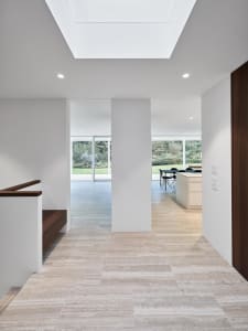 Interior view of a modern kitchen and dining area with marble floors and white walls.