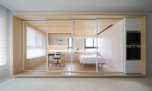 Modern minimalist bedroom featuring a white bed with wooden walls and furniture.