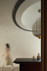A modern minimalist living space featuring a metal chandelier and minimalist decor.