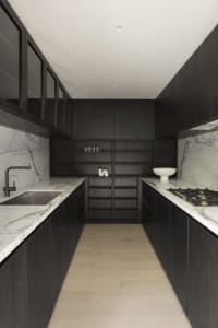 Modern kitchen with marble countertops, dark wooden cabinets, and stainless steel appliances.