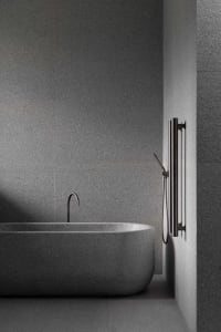 A minimalist industrial bathroom with grey granite bathtub and walls