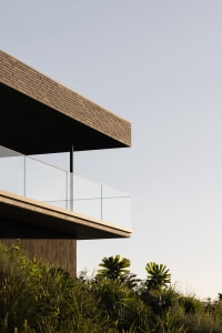 Modern house with glass and brick exterior, featuring a large balcony.