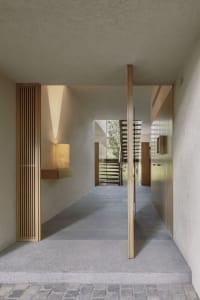 A modern hallway features gray concrete walls, flooring, and stair risers, creating a sleek and minimalist aesthetic.