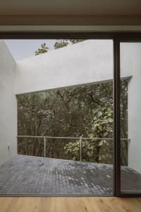 A modern interior space with a metal railing and view of a forested outdoor area.