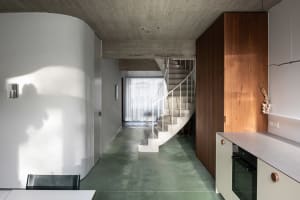 A modern kitchen with a concrete floor and a staircase leading to another level.