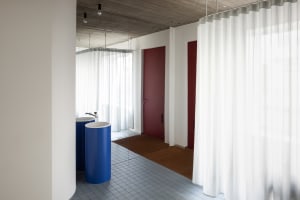 A minimalist office with wooden furniture, white walls, and concrete floors.