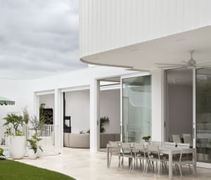 Outdoor patio area with modern furniture, concrete flooring, glass walls, and metal accents.
