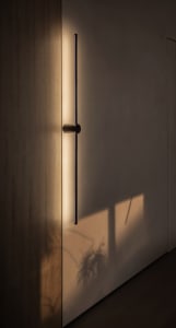 A minimalist metal door handle reflected in a sleek, polished wall, casting a soft shadow.