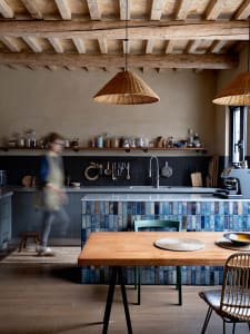 Modern kitchen interior with blue tiles and wooden elements, featuring a spacious dining area and a practical worktop.