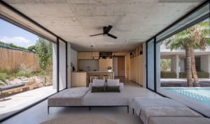 Spacious, minimalist living room featuring a concrete floor and large windows, with a contemporary sectional sofa and a view 