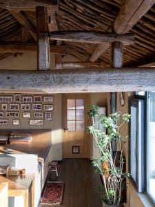 Traditional wooden loft space with an exposed beam ceiling, wooden flooring, and a window.