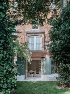A modern brick building with large windows and a green door.